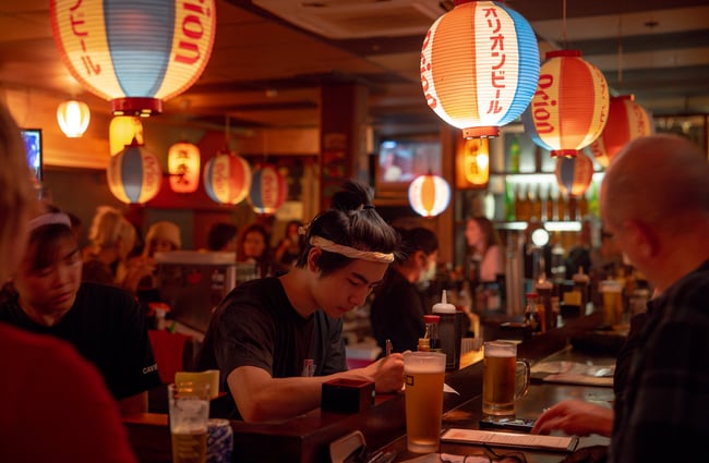 A man working behind a counter inside a busy restaurant.