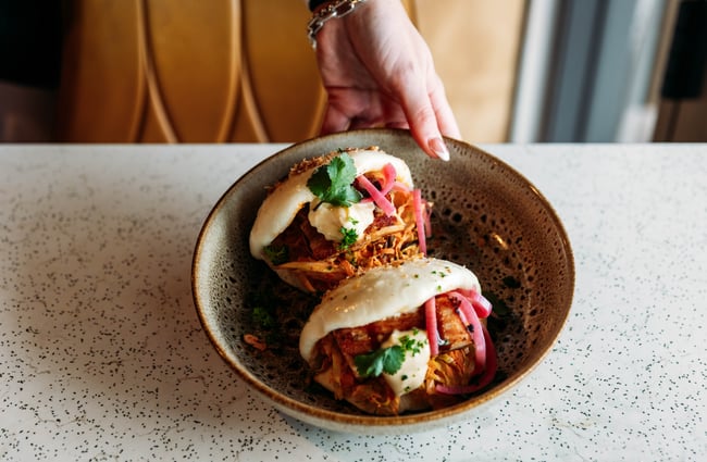 A plate of bao buns is placed on the table at Taper.