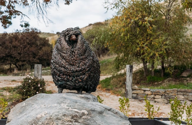 Sheep statue with countryside background in Tarras Village.