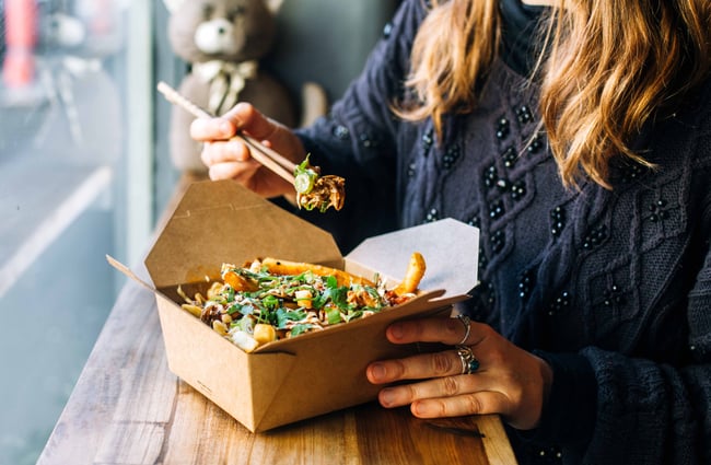 Woman eating box of takeaway noodles.
