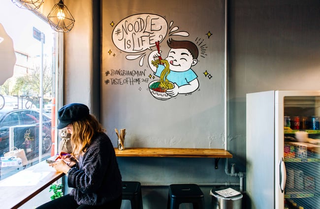 Woman sitting at a window bar on a stool.