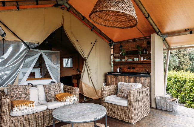 View of the bedroom and outdoor lounge and kitchen at Te Hāpua Coastal Glamping.