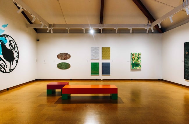 The inside of the gallery with a bench in the middle of the room.
