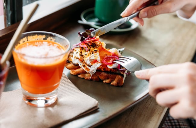 Person cutting into poached egg on top of a piece of focaccia