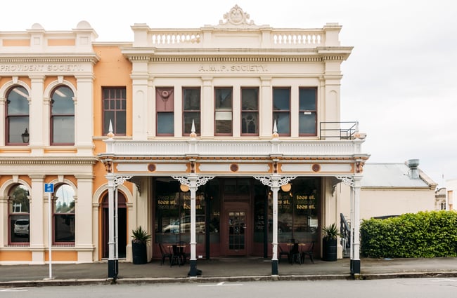 Exterior of Tees St in Ōamaru in a white heritage building with pillars and ornate trimmings