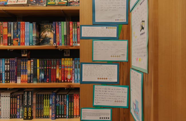 Handwritten book reviews from children displayed on a bookcase at Telling Tales.