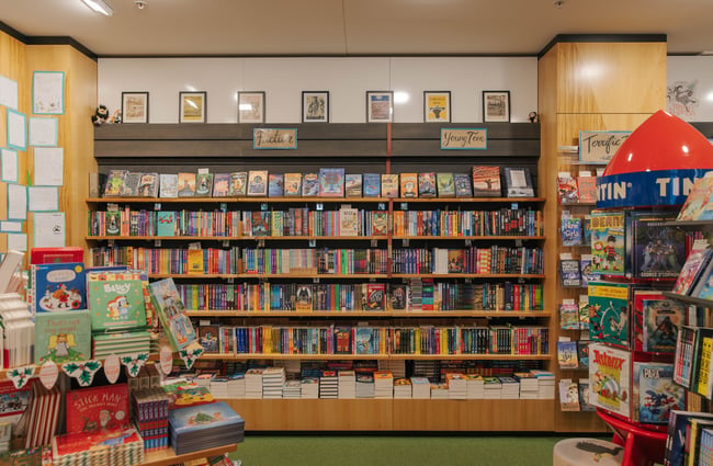 A large bookcase along a wall inside Telling Tales that's lined with fiction and young teen titles.