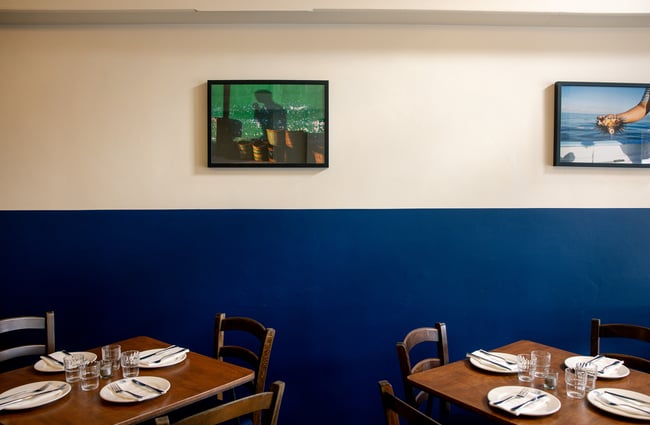 Two table settings against a white and blue wall.