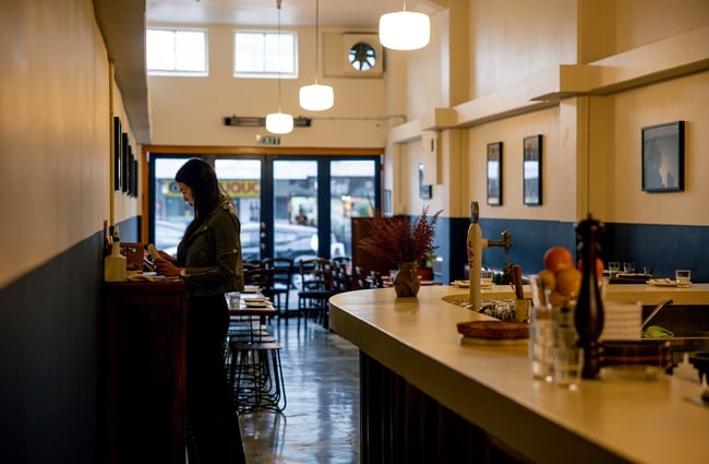 A female staff member at the till inside a dimly lit restaurant.