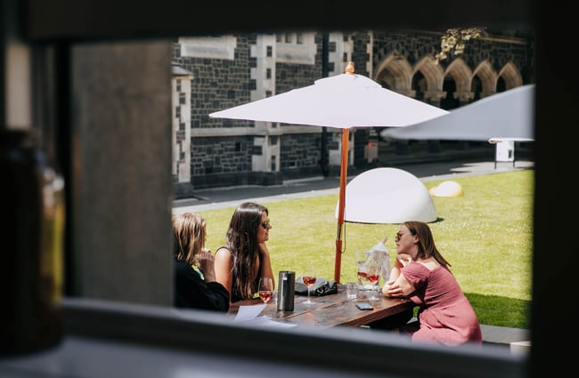 Friends drinking wine in outside courtyard at Cellar Door at The Arts Centre in Christchurch