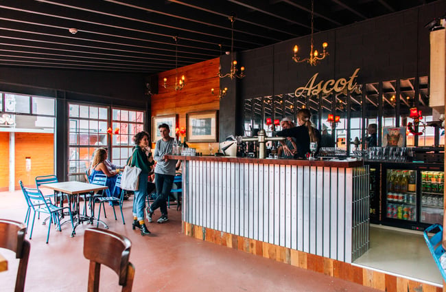 Corrugated iron counter in a large room with tables and chairs and and big factory windows.