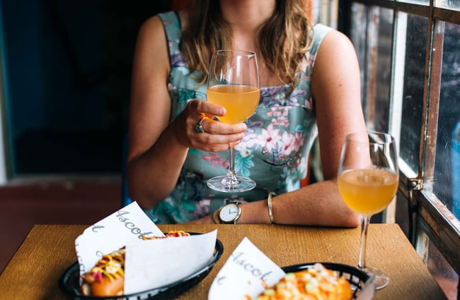Woma drinking a glass of wine in a blue dress.