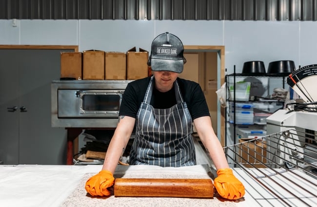 A baker in the kitchen rolling out some dough at The Baked Dane.