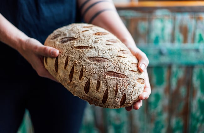 Loaf of sourdough being held by a staff member at The Baked Dane.