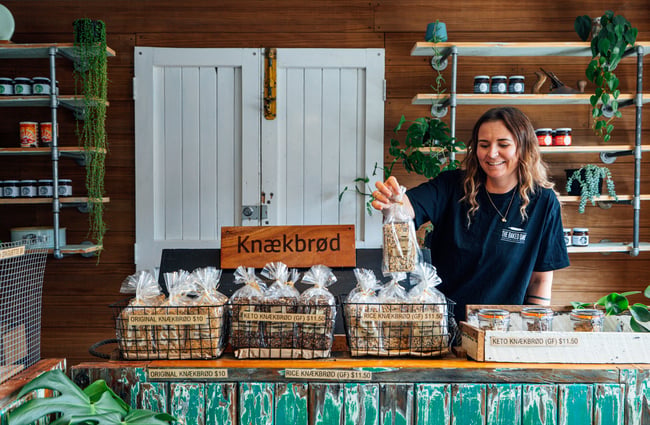 Bakery assistant behind the counter is selecting one of the products from a basket at The Baked Dane.