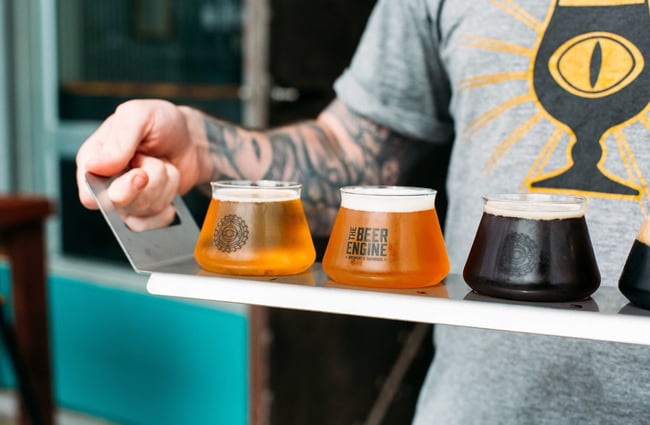 A worker holding a tray of different beer tasters.