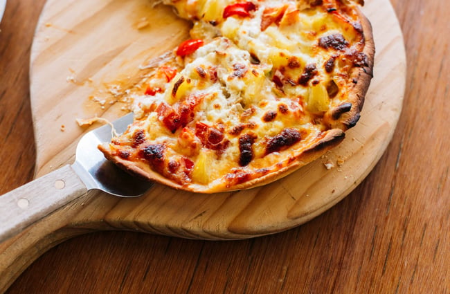 Woman eating pizza on a wooden board.