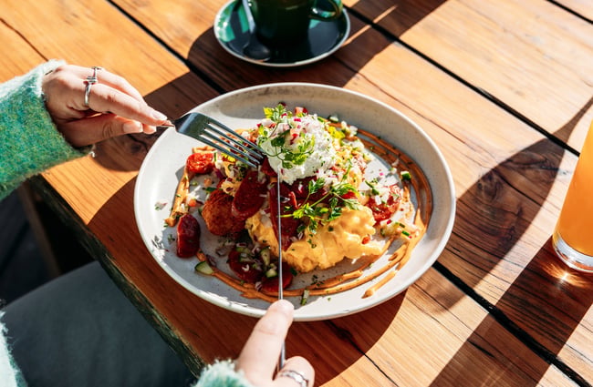 A person eating a plate of scrambled eggs.