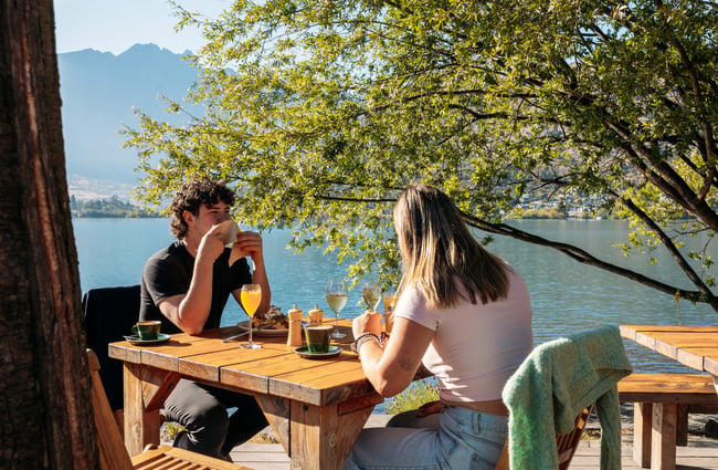 A man and woman eating by the lake at Boat Shed.