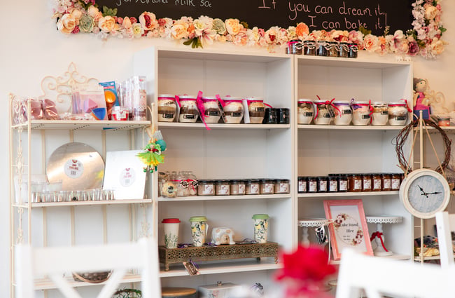 Jars of preserves lined up on white shelves.