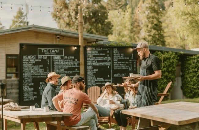 A staff member serving a group of young people outside.