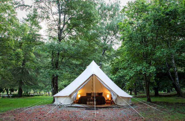 A glamping tent on grass photographed at dusk.
