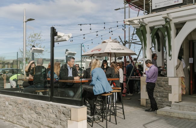 Customers dining outside The Church Pub on a sunny day.