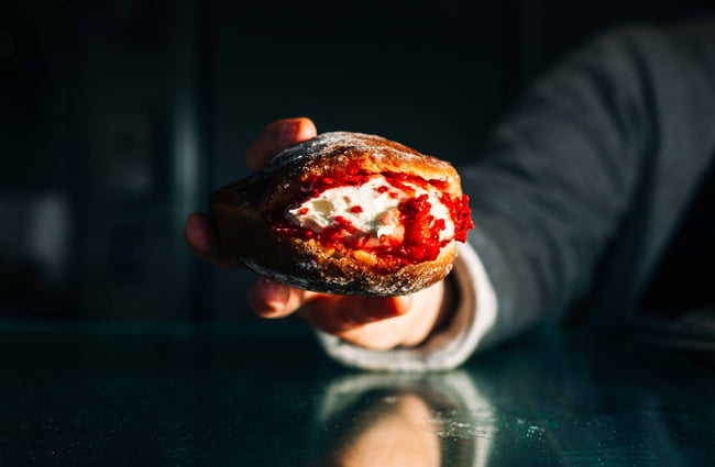 Close up of a person holding a filled doughnut.