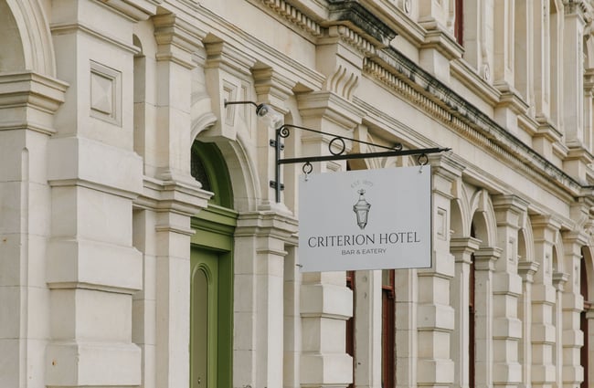 The Criterion Hotel's white sign hanging from the exterior of their stone building
