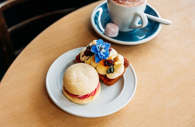 A couple of cakes on a plate with a hot chocolate on a table insideThe Duke’s Roadhouse in Rangitikei.