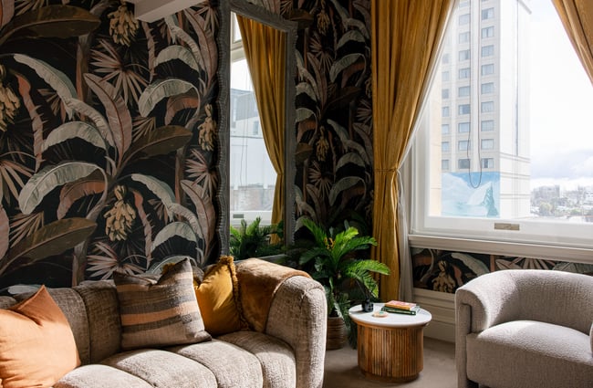 Tropical wallpaper on the walls and a soft looking sofa in The Eve Apartment.