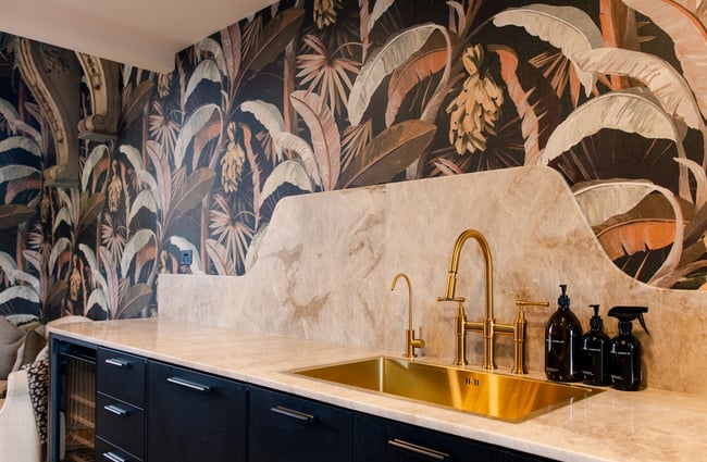 Tropical wallpaper behind the bathroom vanity and sink at The Eve Apartment.