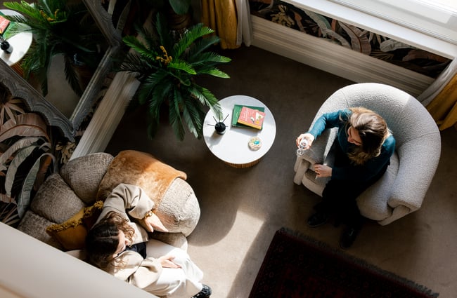 A birds eye view of two guests sitting in the living room from the mezzanine bedroom at The Eve Apartment.