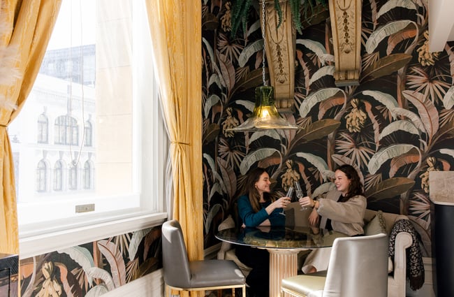 Two guests sitting at the dining table with tropical wallpaper at The Eve Apartment.