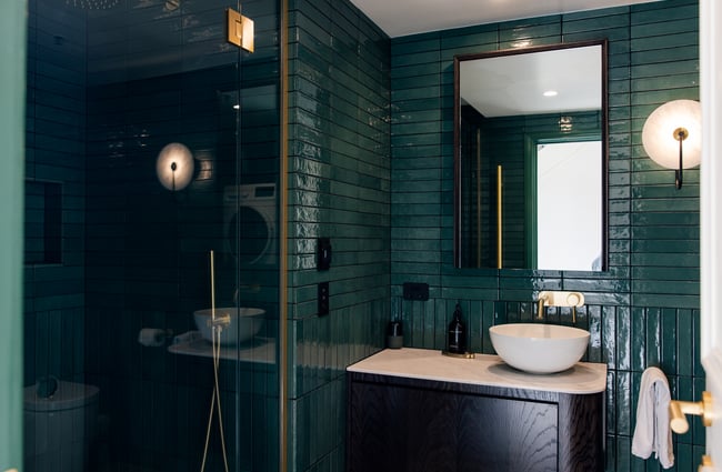 Turquoise bathroom tiles and darker shower glass at The Eve Apartment.