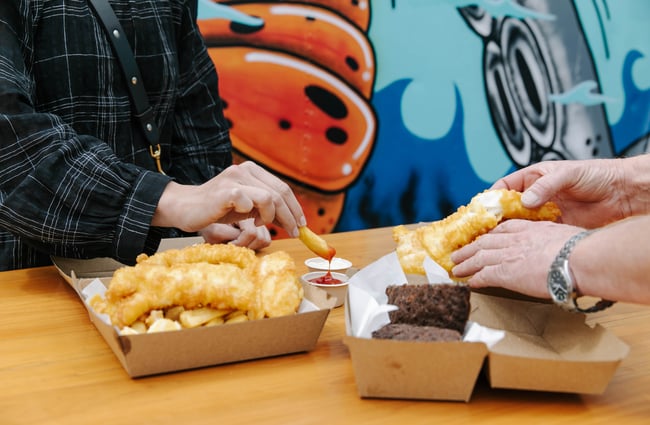 Someone holding a fresh chip being dipped in tomato ketchup at the FishWife in Moeraki.