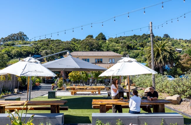 People sitting together under umbrella at outdoor table at The Grand Hotel in Akaroa
