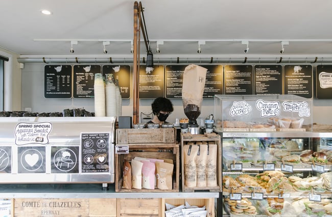 A staff member wearing a mask standing behind the counter at The Greedy Cow Café in Tekapo.