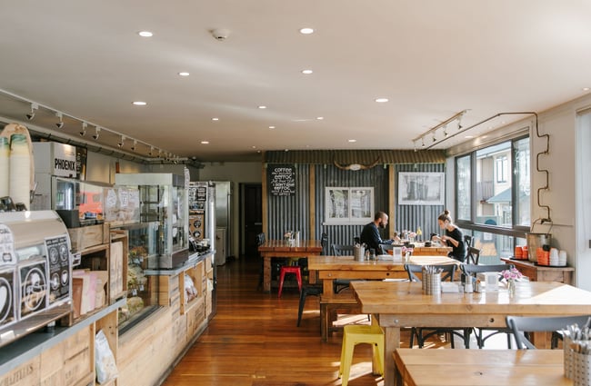 Two customers sitting at a table inside The Greedy Cow cafe in Tekapo.