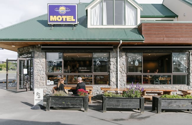 Two women chatting at a table outside The Greedy Cow Café in Tekapo.