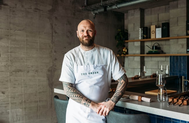 A man in chef whites smiling to camera.