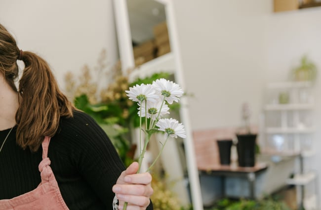 A lady holding a small handful of little white daisies.