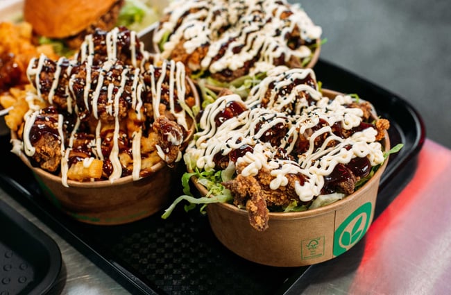 A black tray with three takeaway containers of fried chicken and salads.