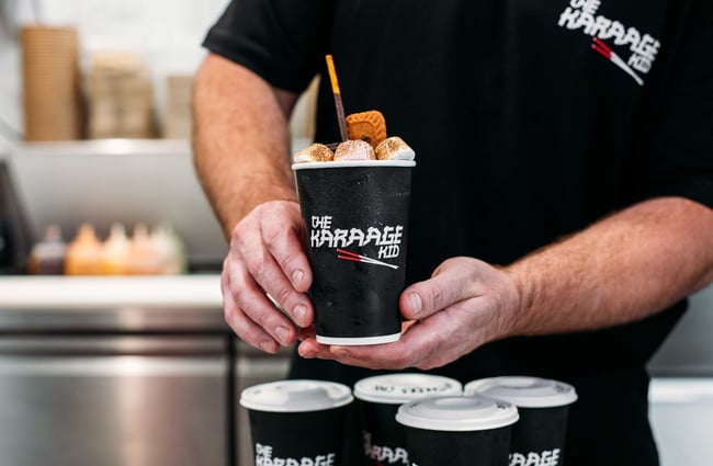 A worker passing a smores hot chocolate across the counter.