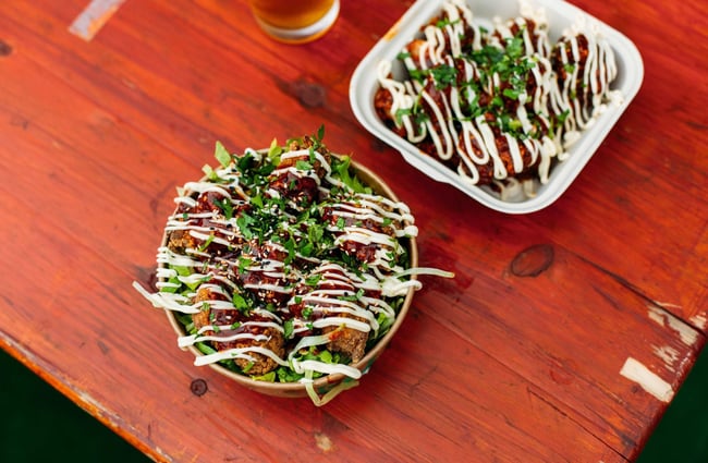 Fried chicken salad with a mayonnaise drizzle in take away containers.