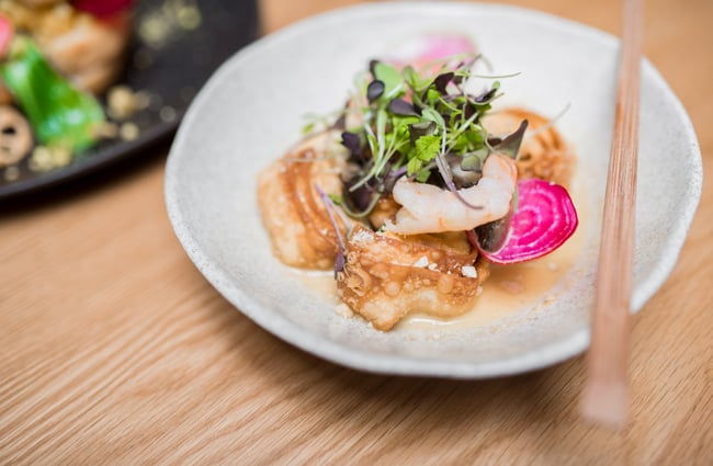Food on a plate next to chopsticks.