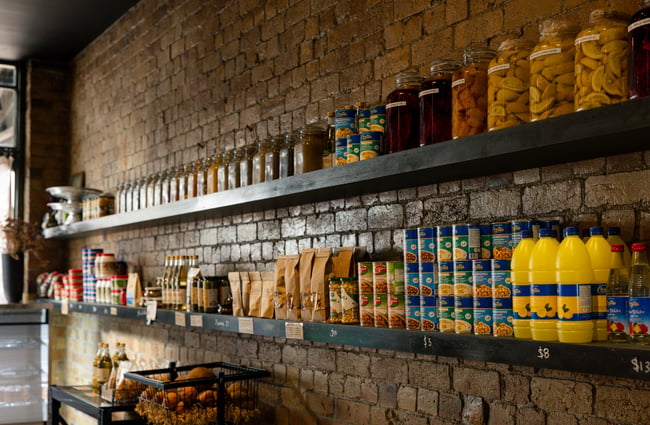 Rows of bottles of condiments lined up in a row on a shelf.