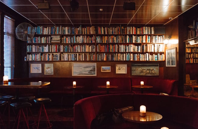 The seating area with tables and chairs inside The Library bar Wellington.
