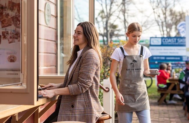 A customer sitting outside and a cafe worker walking past at The Lil Brew Espresso Bar.