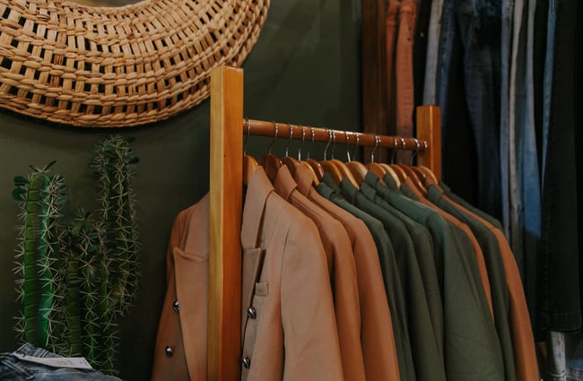 A close up of tan coats on a rack sitting next to fake cactus plants at The Red Little Fox store in Fairlie.